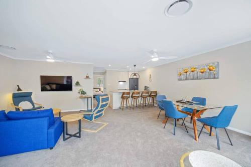 a living room with blue chairs and a dining room at Flynns Beach Resort - Port Macquarie beachside apartment - Flynn114 in Port Macquarie