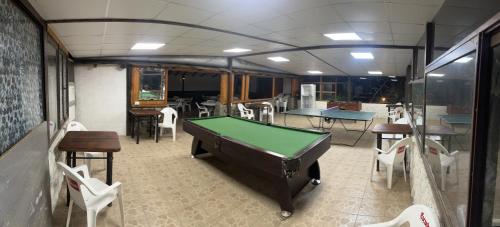 um quarto com uma mesa de bilhar e mesas e cadeiras em CASARMONIA em Peumos