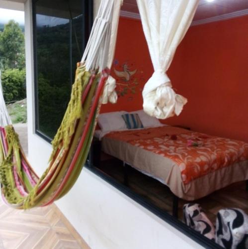 a room with a bed and a hammock at Hosteria Cercaloma in Santa Isabel