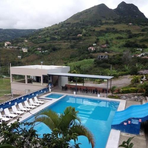 ein großer Pool mit Stühlen und ein Gebäude in der Unterkunft Hosteria Cercaloma in Santa Isabel