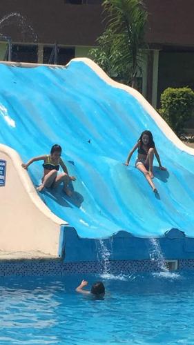 zwei Kinder auf einer blauen Rutsche im Wasser in der Unterkunft Hosteria Cercaloma in Santa Isabel