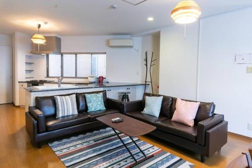 a living room with a leather couch and a table at Osaka190sqm specious private house max21ppl in Osaka