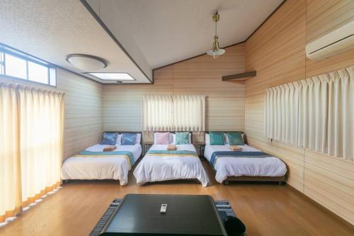 a room with three beds and a table in it at Osaka190sqm specious private house max21ppl in Osaka