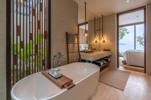 a bathroom with a tub and a sink and a bed at Cape Fahn Hotel - Private Islands Samui in Choeng Mon Beach