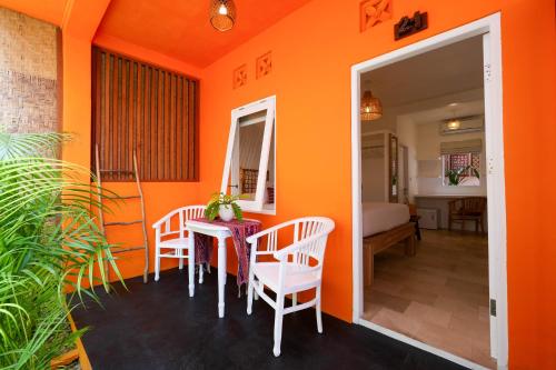 a dining room with orange walls and a table and chairs at The Room Padang-Padang in Uluwatu