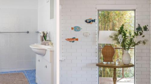 a bathroom with a toilet and a vase on a table at Bimbajong Yamba - oceanstays in Yamba