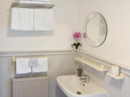 a bathroom with a sink and a mirror and towels at Hunters Cottage - Uk44956 in Pooley Bridge