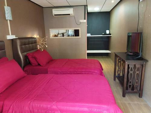 ein Schlafzimmer mit einem rosa Bett und einem TV in der Unterkunft TAMARA GUEST HOUSE in Tioman Island