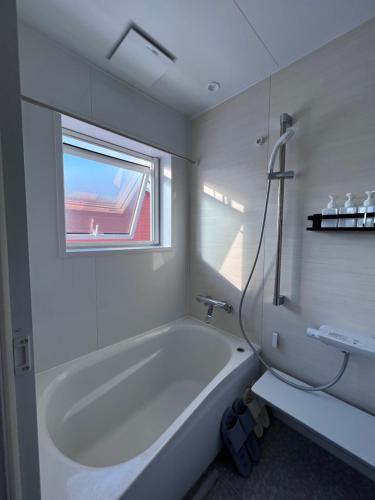 a white bathroom with a tub and a window at THE LOBS, RUSUTSU in Kimobetsu