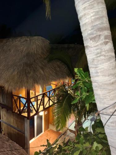 a building with a thatched roof and a palm tree at Blue House in Puerto Escondido