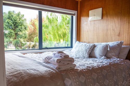 a bed with towels on it in front of a window at Honey Cottage in Ettrick in Millers Flat