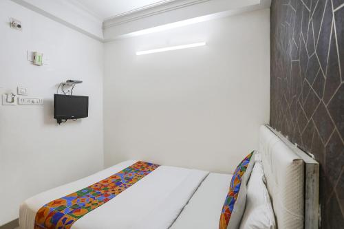 a bedroom with a bed and a tv on a wall at FabExpress Greenstar Inn - Bhubaneswar Airport in Bhubaneshwar