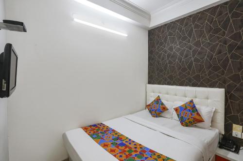 a bedroom with a white bed with colorful pillows at FabExpress Greenstar Inn - Bhubaneswar Airport in Bhubaneshwar