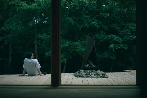 einem Mann, der vor einem Kamin sitzt in der Unterkunft The VILLA KAORU in Otaru