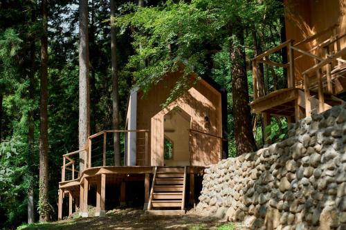 a house in the woods with a stone wall and stairs at 自然人村 in Akiruno