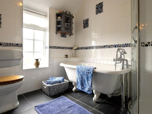 a bathroom with a tub and a toilet and a sink at Crows Cottage in Fishguard