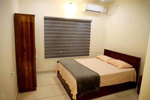 Habitación pequeña con cama y ventana en Clover Home en Thiruvalla