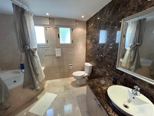 a bathroom with a sink and a toilet and a tub at SeaView 5 Bedroom Villa with Private Pool in Limassol