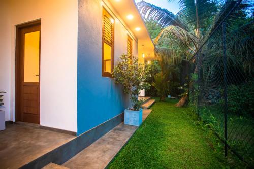 a house with a blue wall and a yard at The Shades Galle in Galle