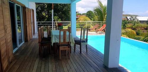 a deck with a table and chairs next to a swimming pool at Villa Lavany in Nosy Be