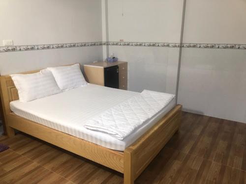 1 dormitorio con 1 cama con sábanas blancas y almohadas blancas en NHÀ NGHỈ LONG VIÊN, en Hàm Tân