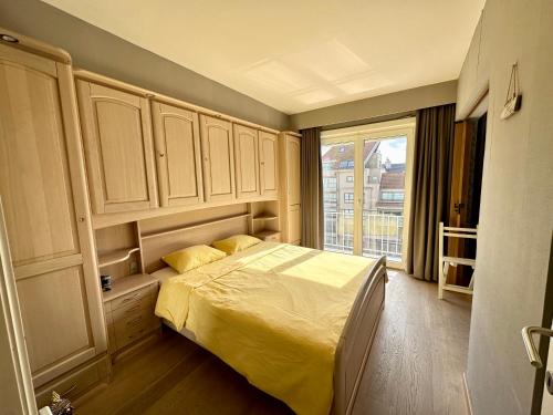 a bedroom with a bed and a large window at Charming Apartment direct access beach Blankenberge in Blankenberge