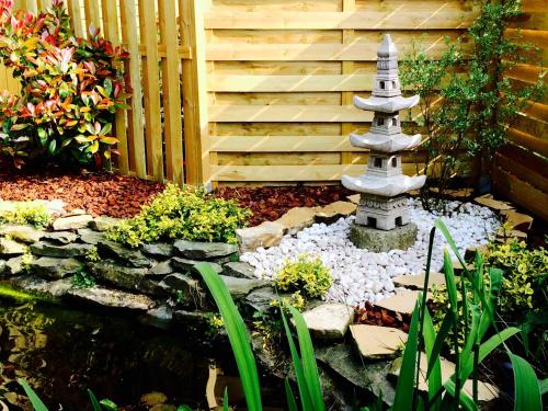 a stone fountain in a garden with a staircase at Au chalet d'Isa in Havelange
