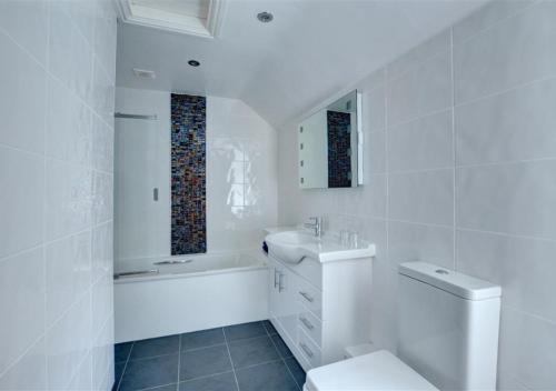 Baño blanco con aseo y lavamanos en Ty Nain en Caernarfon
