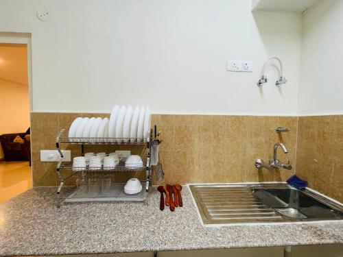 um balcão de cozinha com um lavatório e copos brancos numa prateleira em ALanKrita Homes em Lucknow
