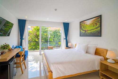 a bedroom with a bed and a desk and a window at White House Central Villa in Hoi An