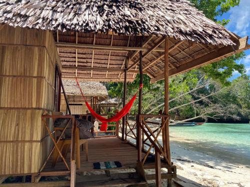 a hut with a hammock on a beach at I&D Home Stay Raja Ampat in Yennanas Besir