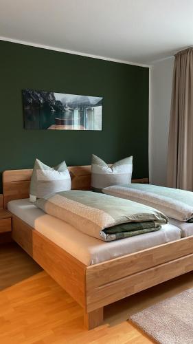 Cama grande en habitación con pared verde en haustierfreundliche Ferienwohnung Greifenbach en Geyer