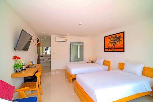a hotel room with two beds and a desk and a television at White House Central Villa in Hoi An