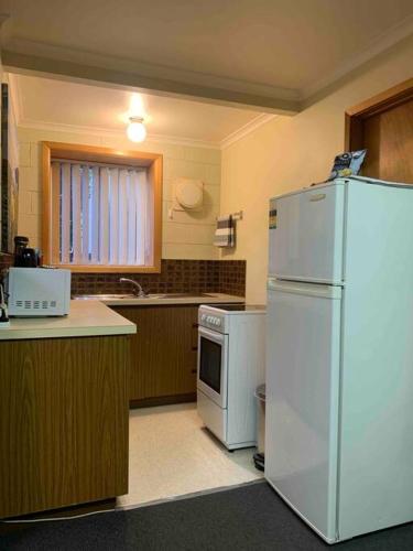 a kitchen with a white refrigerator and a stove at Wombats Den A warm and cosy semi underground retreat in Howrah