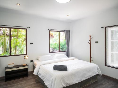 a white bedroom with a bed and two windows at Sand Beach Bungalow in Klong Muang Beach