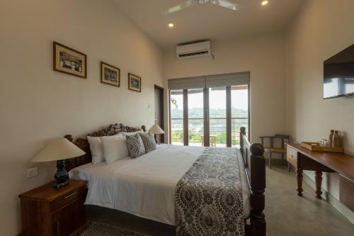a bedroom with a bed and a desk and a window at Edgar Mansion Kandy in Kandy