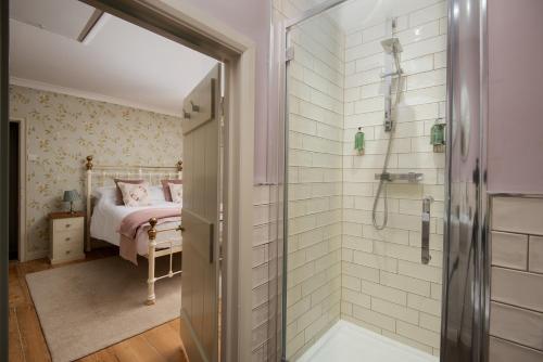 a bathroom with a shower and a bed at Owl Cottage in Morpeth