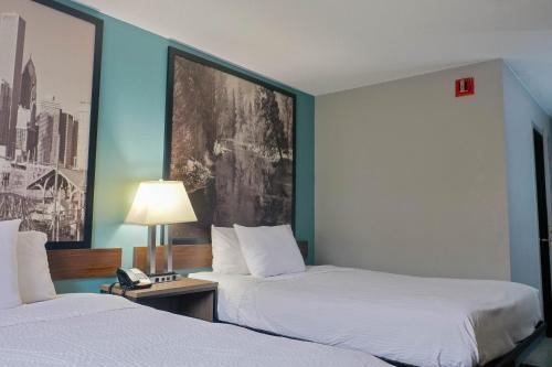 a hotel room with two beds and a phone on a table at Super 8 by Wyndham Rockford I-90 Casino District in Rockford
