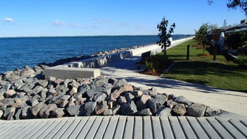 a pile of rocks on a sidewalk next to the water at Beachmere Palms Motel in Beachmere