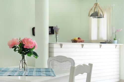 a table with a vase of pink flowers on it at Triantafilia Guesthouse in Áyioi Apóstoloi
