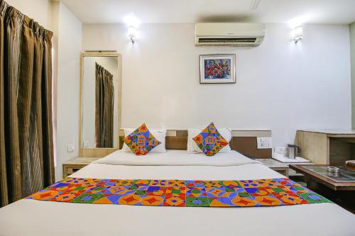 Un dormitorio con una cama con una manta de colores. en FabHotel Smriti Star, en Bhopal