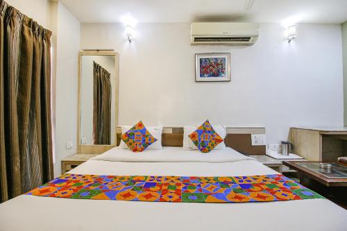 a bedroom with a bed with a colorful blanket on it at FabHotel Smriti Star in Bhopal
