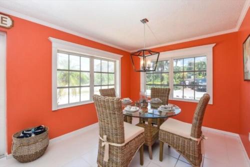 a dining room with orange walls and a table and chairs at Gulf Home #56546 in Holmes Beach