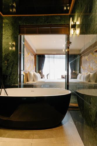 a large bath tub in a room with a bedroom at La Passion Hanoi Hotel & Spa in Hanoi