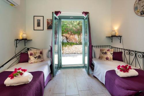 two beds in a room with a glass door at Red Rose Artistsvillas in Gaios