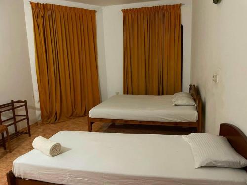 two beds in a room with orange curtains at Mimosha Holiday Inn in Rambukkana