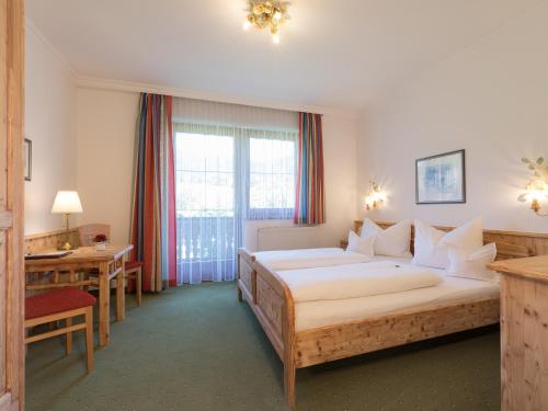 a hotel room with a large bed and a desk at Landhotel Häuserl im Wald in Gröbming