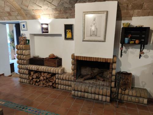 a living room with a stone fireplace with logs at L'Olivera Casa Rural in Castellbisbal