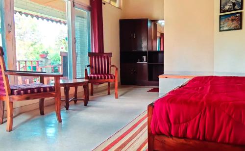 a bedroom with a bed and a table and chairs at Majkhali Woods, Ranikhet, By Himalayan Eco Lodges in Rānīkhet