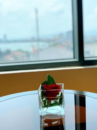 a red rose in a glass vase on a table at Muong Thanh Luxury Nhat Le Hotel in Dong Hoi